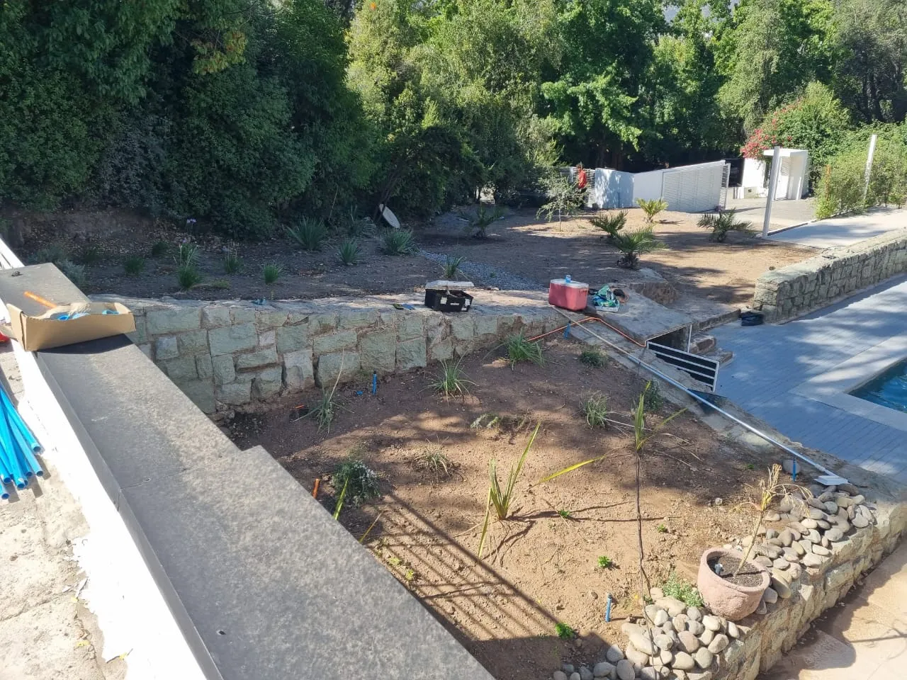 Jardín curvo con muro de piedra y banca integrada