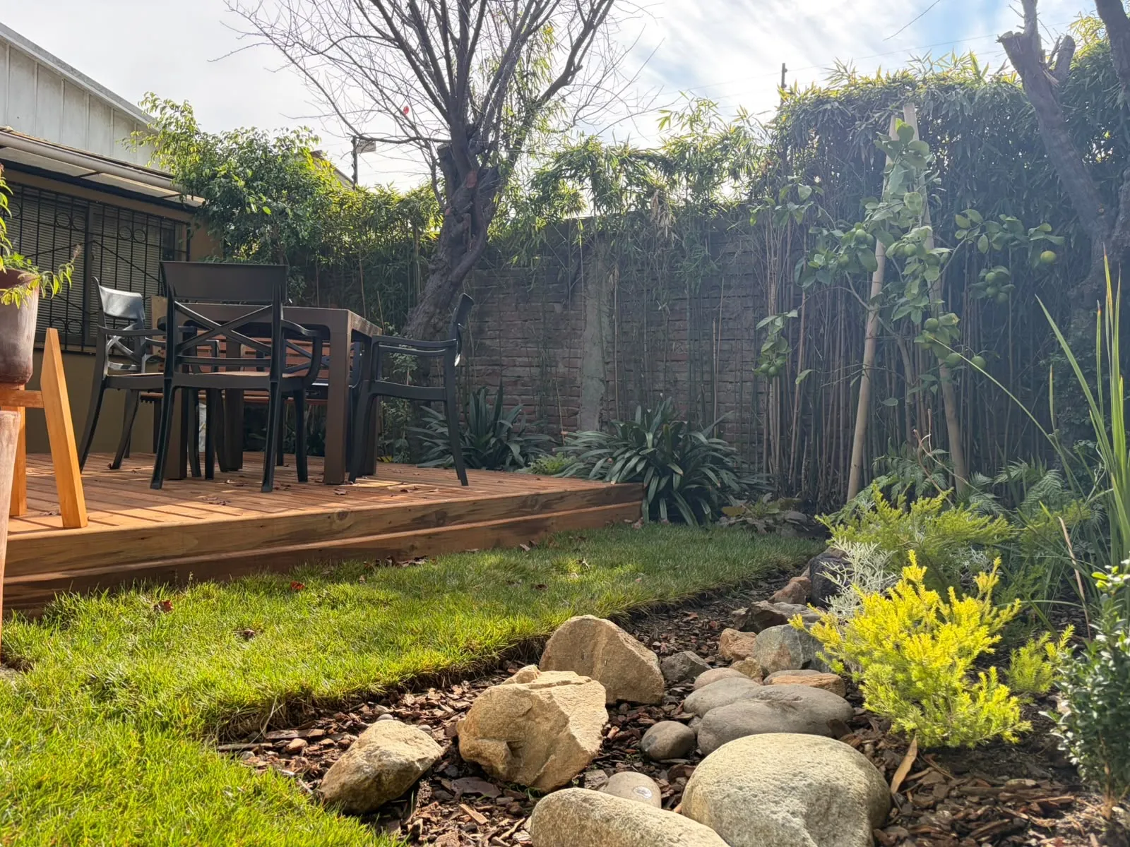 Jardinera de roca con floración amarilla junto al deck
