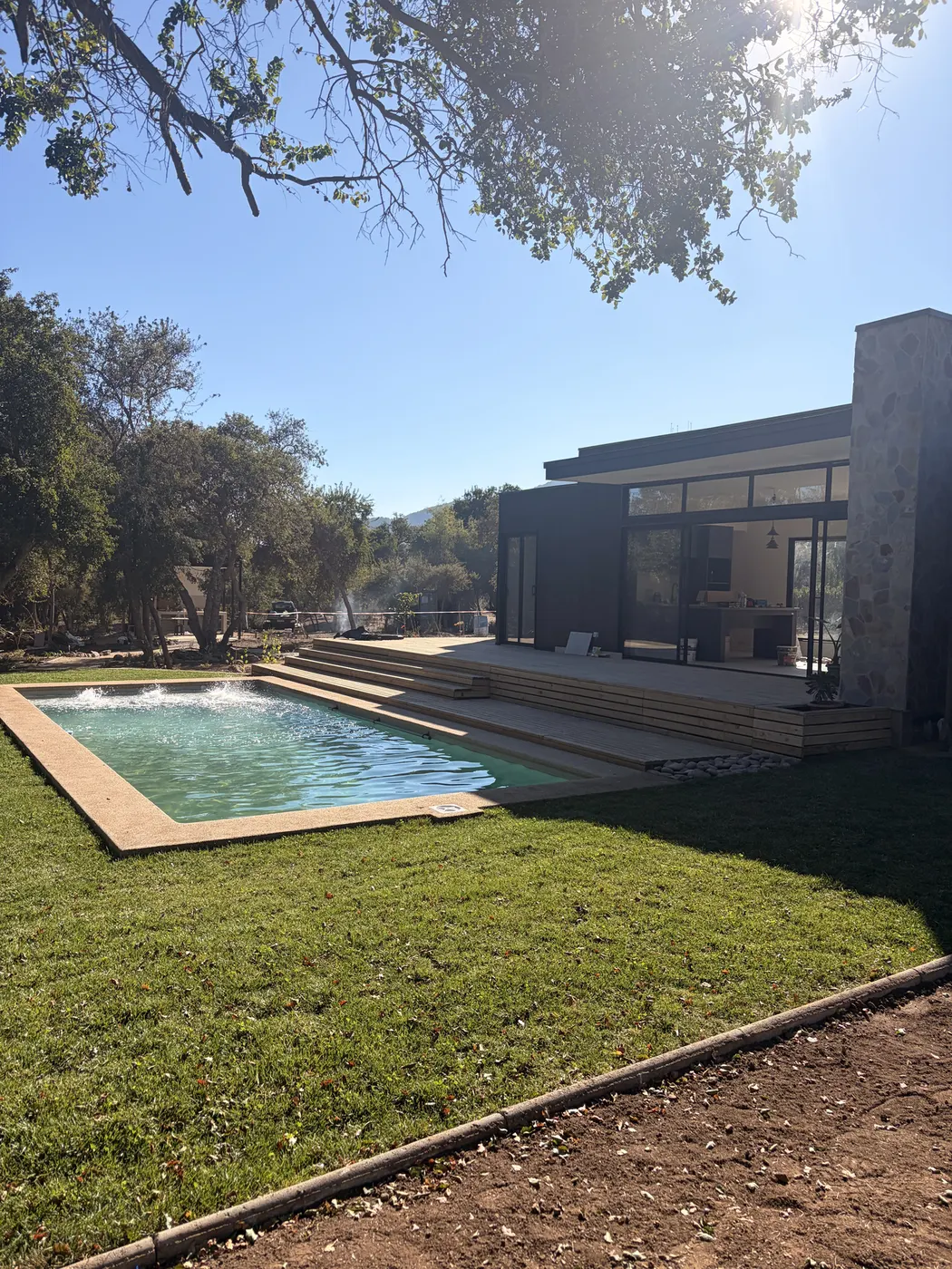 Jardín de césped con piscina frente a casa moderna