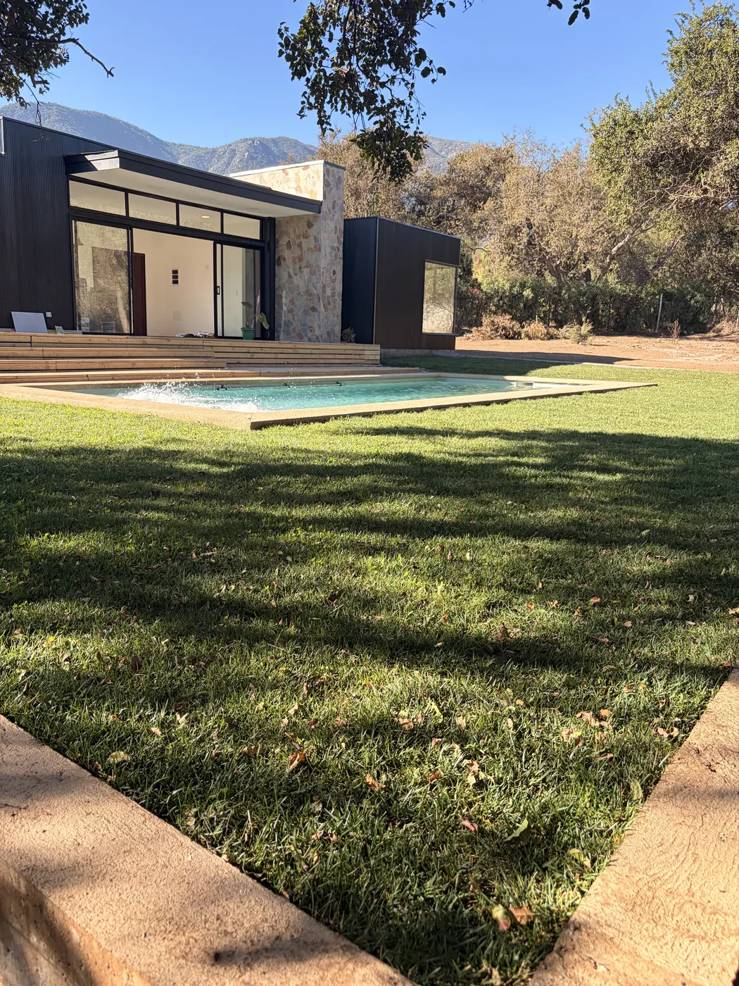 Terraza de madera integrada al jardín con árboles nativos